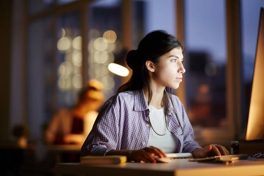 Frau sitzt abends am Schreibtisch