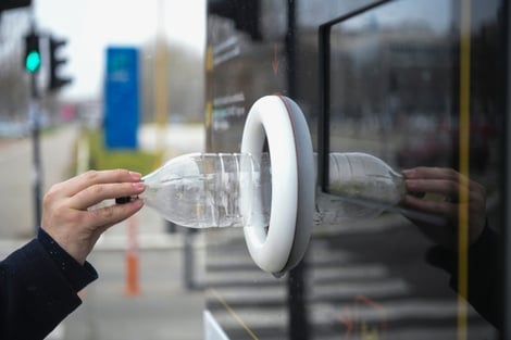 Person schiebt Plastikflasche in Leergutautomaten