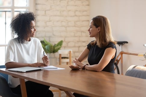 zwei Frauen sitzen sich unterhaltend am Tisch