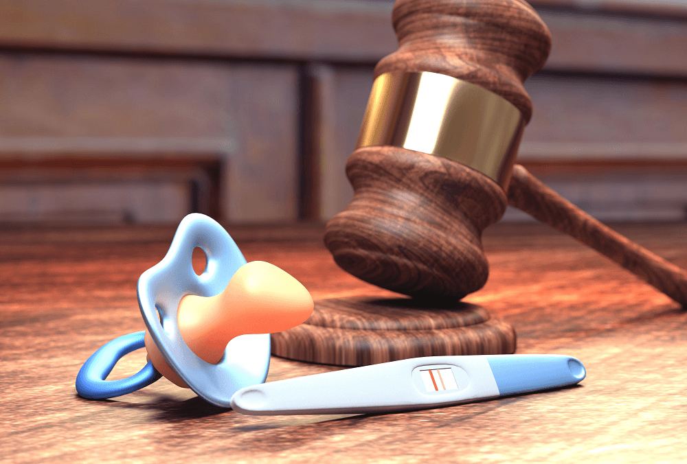 Schnuller mit Richterhammer und Schwangerschaftstest - Schwangerschaft im Arbeitsrecht