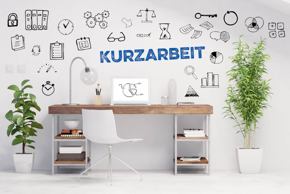 Kurzarbeit-Schriftzug auf Wand mit Schreibtisch und Stuhl